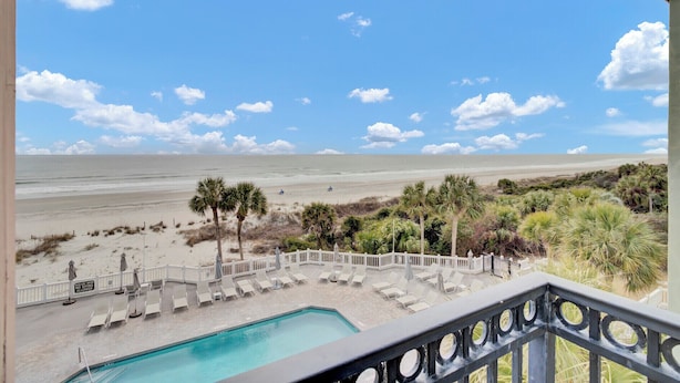 A pool area with a view of the beach and ocean.