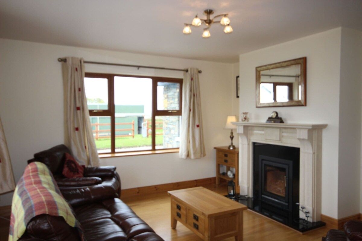 A living room with a fireplace, leather sofa, wooden coffee table, and a window with curtains.