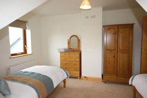 A bedroom with a bed, dresser, wardrobe, and a window.