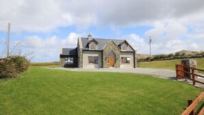 Une maison à deux étages avec une façade en pierre, un porche à l’avant et une pelouse bien entretenue.