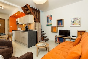 Una sala de estar moderna con un sofá, una mesa de centro y una zona de cocina con una escalera.