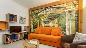 Un salon avec un meuble TV en bois, un canapé orange, un canapé marron et une table basse sur laquelle repose un livre.