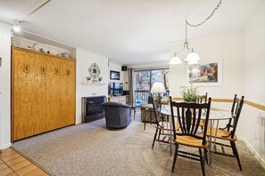 A hotel room with a dining area, a fireplace, a TV, and a balcony with a view.