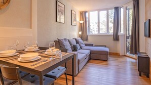 A modern living room with a dining area, a sofa, a TV, and large windows. - A central, one bedroom apartment, perfect for a couple or small group. (Chamonix-Mont-Blanc)