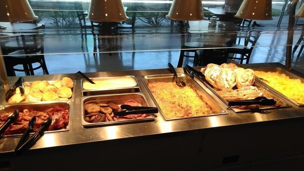 A buffet with various food items including pastries, meats, and grains.