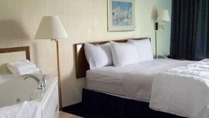 A hotel room with a bed, a bathroom with a sink and mirror, and a painting on the wall.