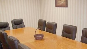 A conference room with a long wooden table and eight black leather chairs.