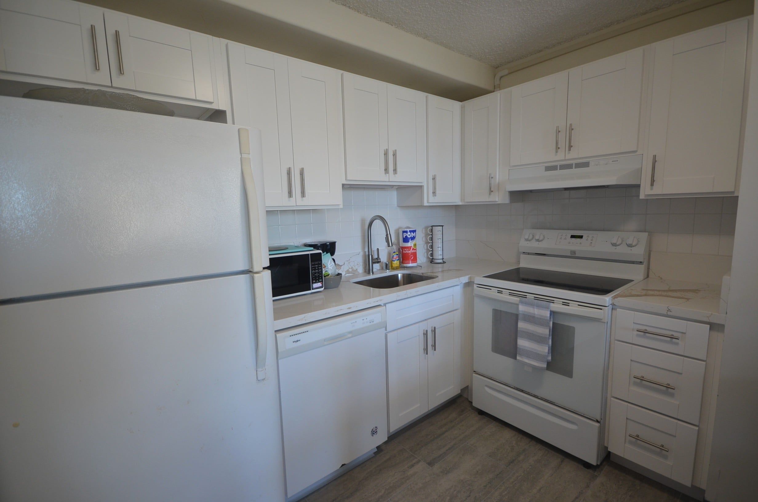 A kitchen with white cabinets, a microwave, a stove, and a dishwasher.