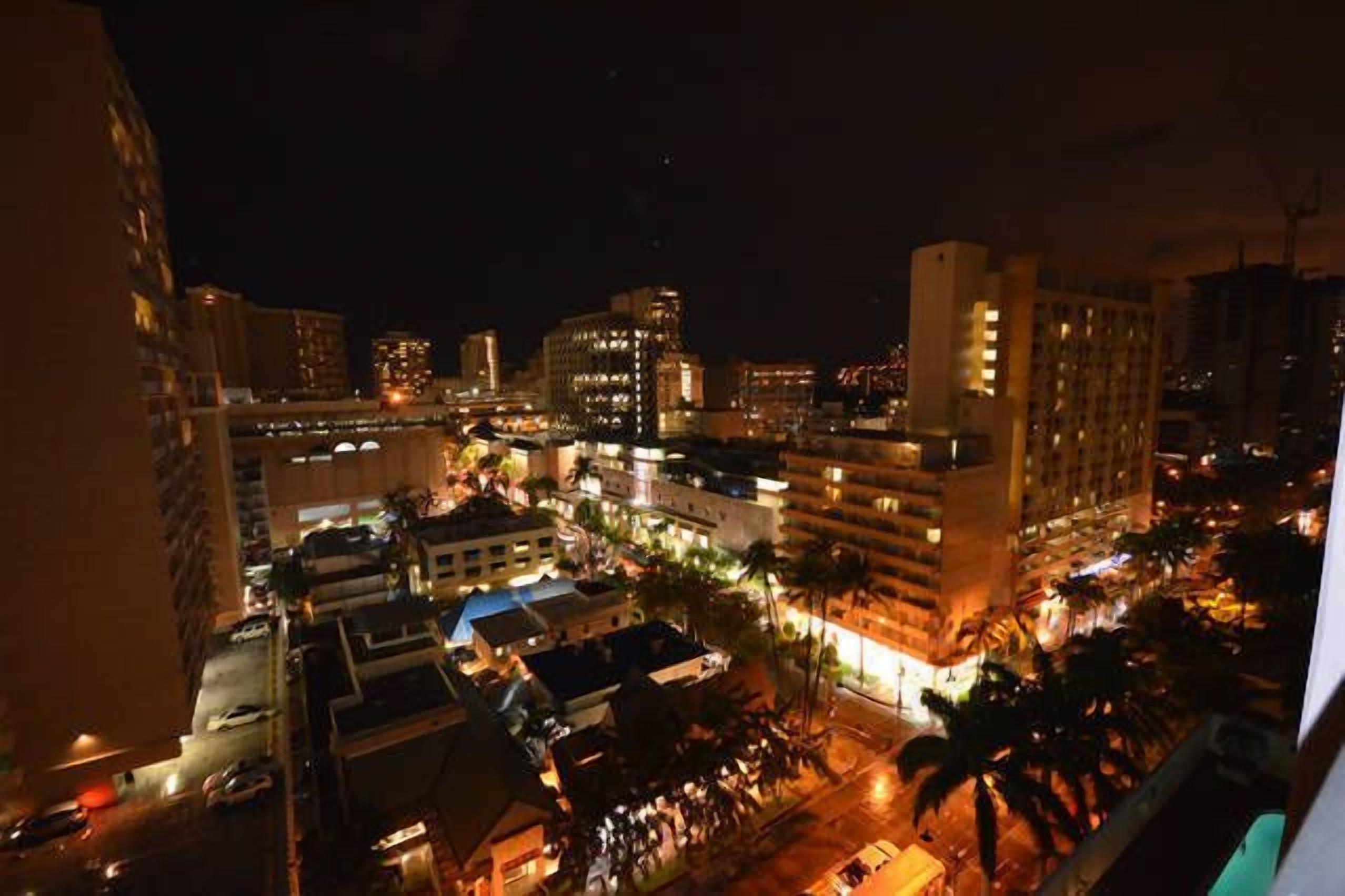 A nighttime cityscape with illuminated buildings and a busy street.