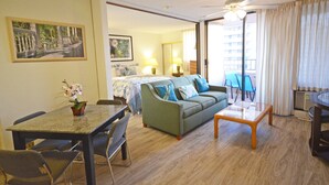 A room with a dining table, chairs, a sofa, a coffee table, and a ceiling fan. - Royal Kuhio 1309 with King Bed, FREE Parking/WiFi, mins to BEACH! (Honolulu)