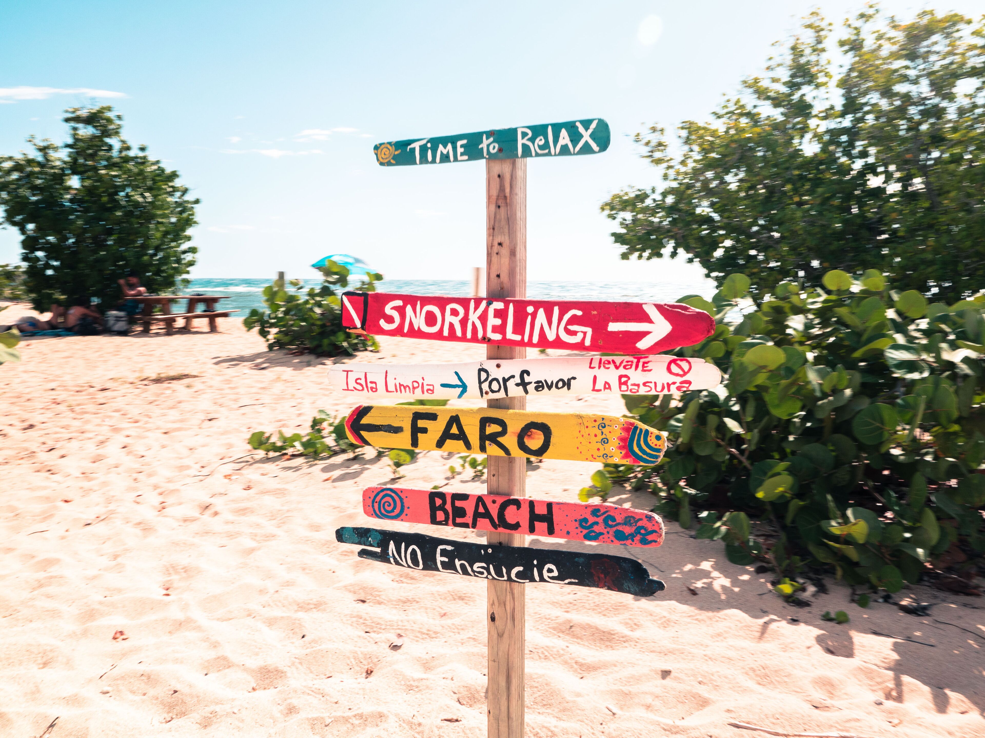 A beach signpost with directions to various activities.