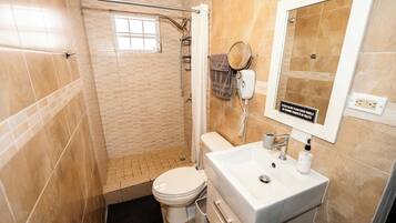 Une salle de bain comprenant des toilettes, un lavabo et un espace douche.