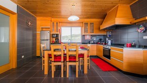 A modern kitchen with wooden cabinets, a central island, and a red rug.