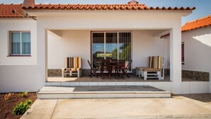 A modern house with a patio, a dining table with chairs, and a large sliding glass door.