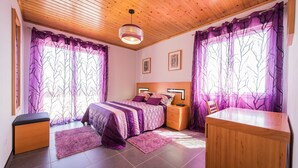 A bedroom with a bed, bedside tables, a desk, and a chair.