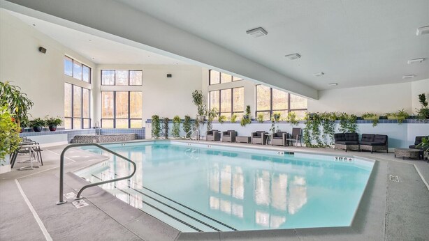 An indoor swimming pool with clear water, surrounded by lounge chairs and potted plants. - Ski on/ski off, conveniently located with beautiful views, Sunrise B3 (Killington)
