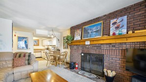 A cozy living room with a fireplace, a dining area, and a kitchen. - Ski on/ski off, conveniently located with beautiful views, Sunrise B3 (Killington)