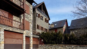 Ein traditionelles Steinhaus mit hölzernen Balkonen und Garagentoren.