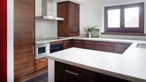 Eine moderne Küche mit Holzausstattung, einem Edelstahlbackofen und einer großen Kücheninsel mit Granitplatte.