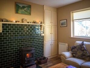 A cozy living room with a fireplace, a white cabinet, a cushioned sofa, and a window with a view. - Lough Fee, Renvyle (Renvyle)