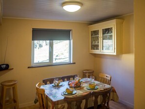 A dining area with a table set for four, a window with blinds, and a cabinet above the window. - Lough Fee, Renvyle (Renvyle)