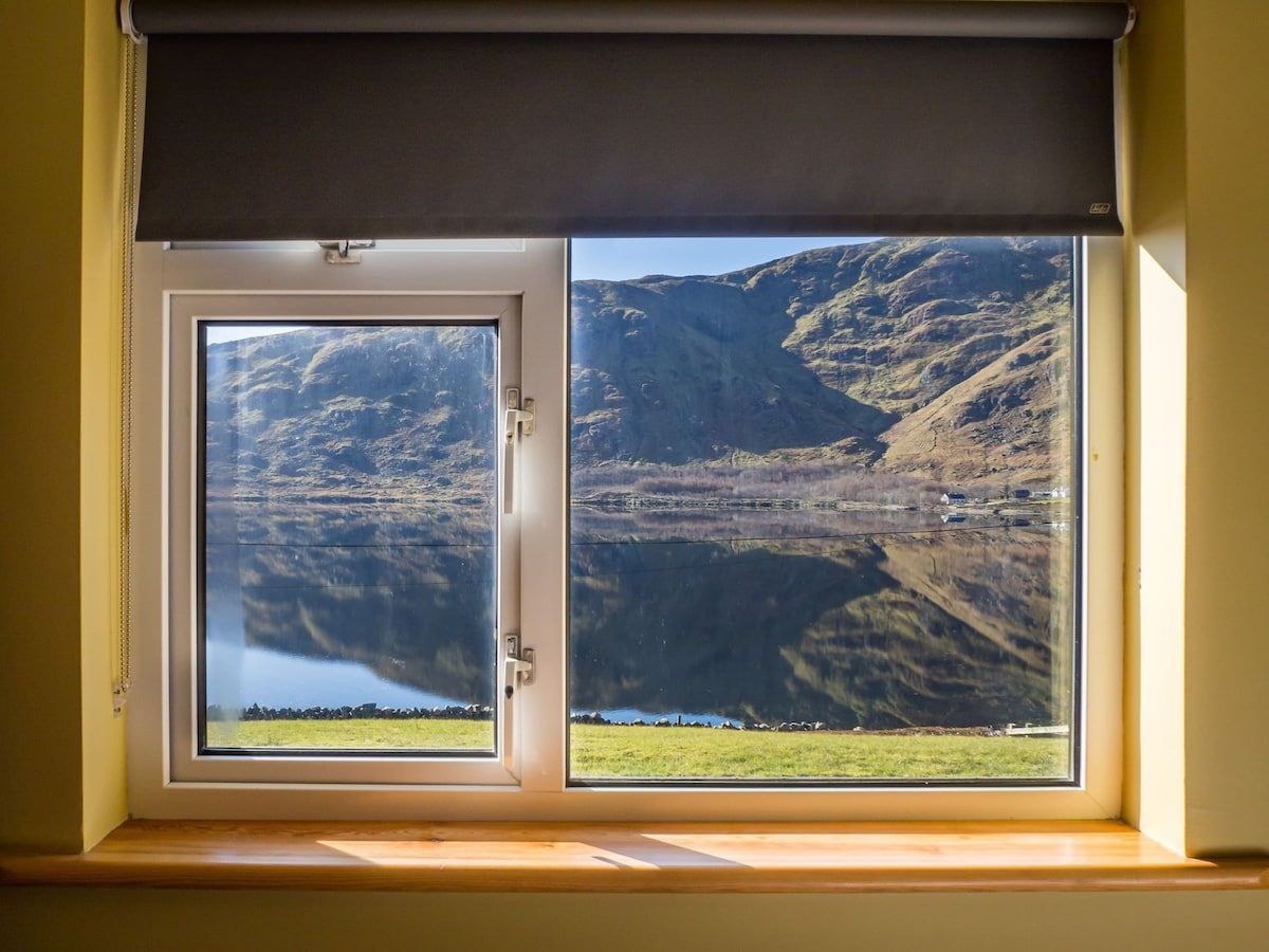 A window with a view of a mountainous landscape and a body of water.
