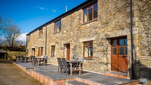A stone building with a patio area featuring outdoor seating. - 4* self catering, farm stay cottage. Sleeps 4 (Boscastle)