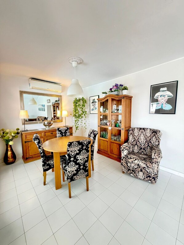 A dining area with a wooden table and chairs, a cabinet with glass doors, and a hanging plant.