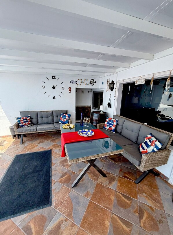 Un salon avec une table basse en verre, un canapé gris et un chemin de table rouge.