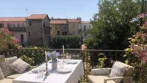 Un área de comedor al aire libre con una mesa dispuesta para cuatro personas, rodeada de sillas acolchadas.