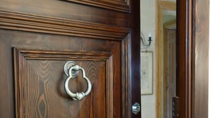 A wooden door with a metal handle and a decorative panel. - Spacious Apartment- historical character- fascinating views over old town & sea (Valletta)