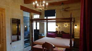 A bedroom with a four-poster bed, a wooden chair, a table, and a chandelier. - Spacious Apartment- historical character- fascinating views over old town & sea (Valletta)
