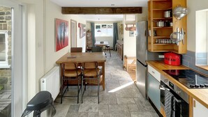 Een moderne keuken met een eethoek, houten balken en een rode broodtrommel.