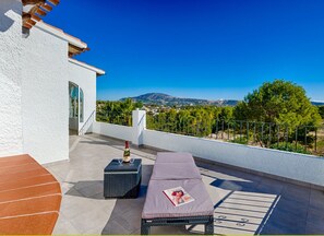 Una terraza con una cama, una mesa y una botella de vino. Tiene vistas al paisaje.