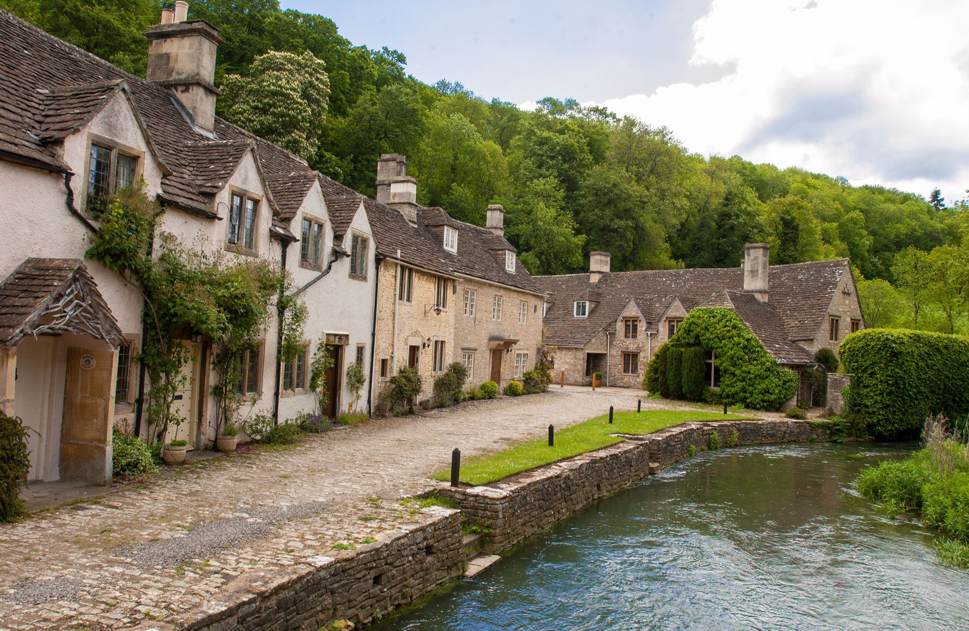 A row of stone buildings with a river in the foreground.