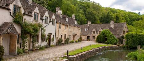 A row of stone buildings with a river in the foreground.
