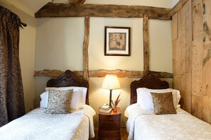 A room with two beds, a wooden headboard, a lamp, and a framed picture on the wall.