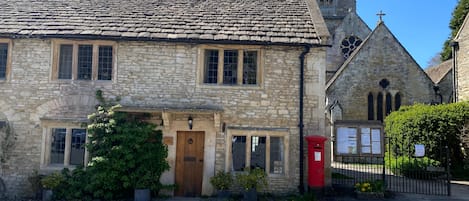 A stone building with a traditional design, featuring a prominent tower and a red post box.