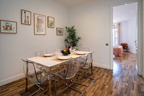 Comedor con una mesa dispuesta para cuatro personas, sillas transparentes y un centro de mesa con planta.