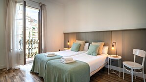 A hotel room with two beds, a small table, a chair, and a balcony with a view of buildings. - Barcelona Balconies 4 - Habitat Apartments (Barcelona)