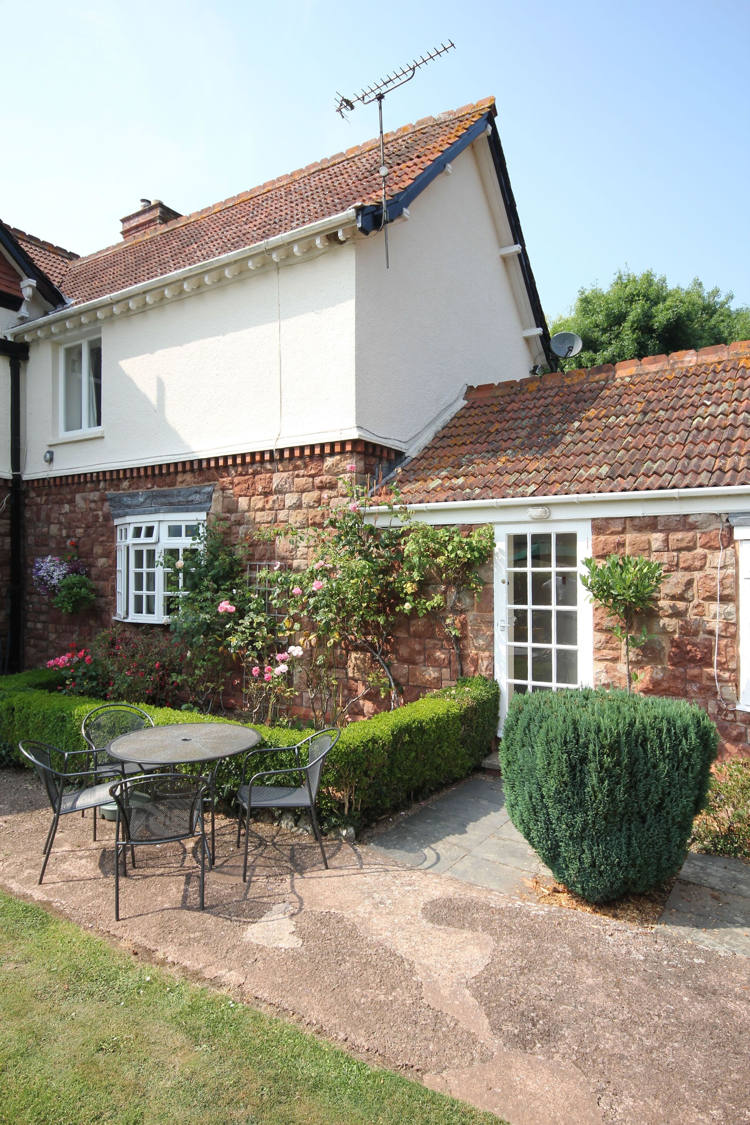 A house with a garden patio, a white exterior, and a brick facade.