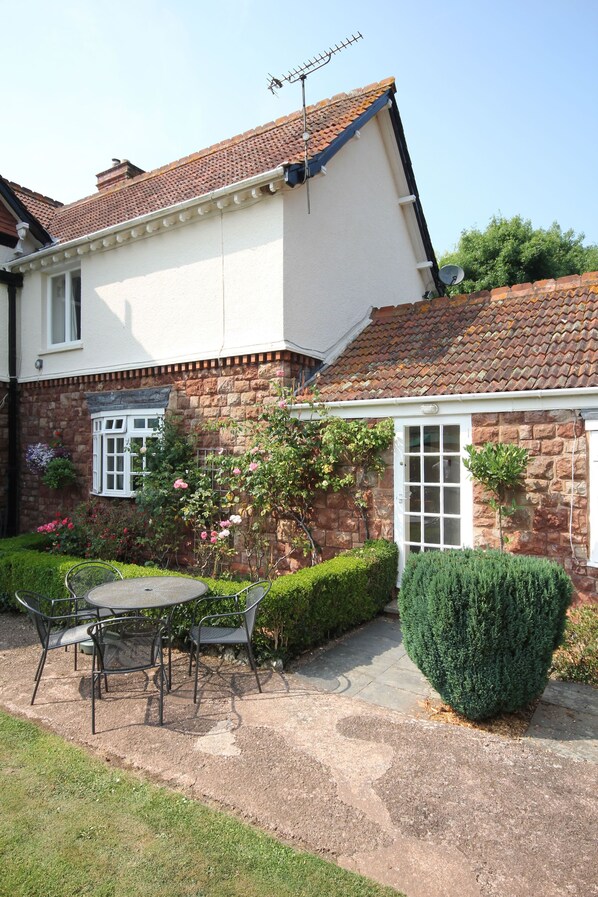 Een huis met een tuinpatio, een witte gevel en een bakstenen voorgevel.