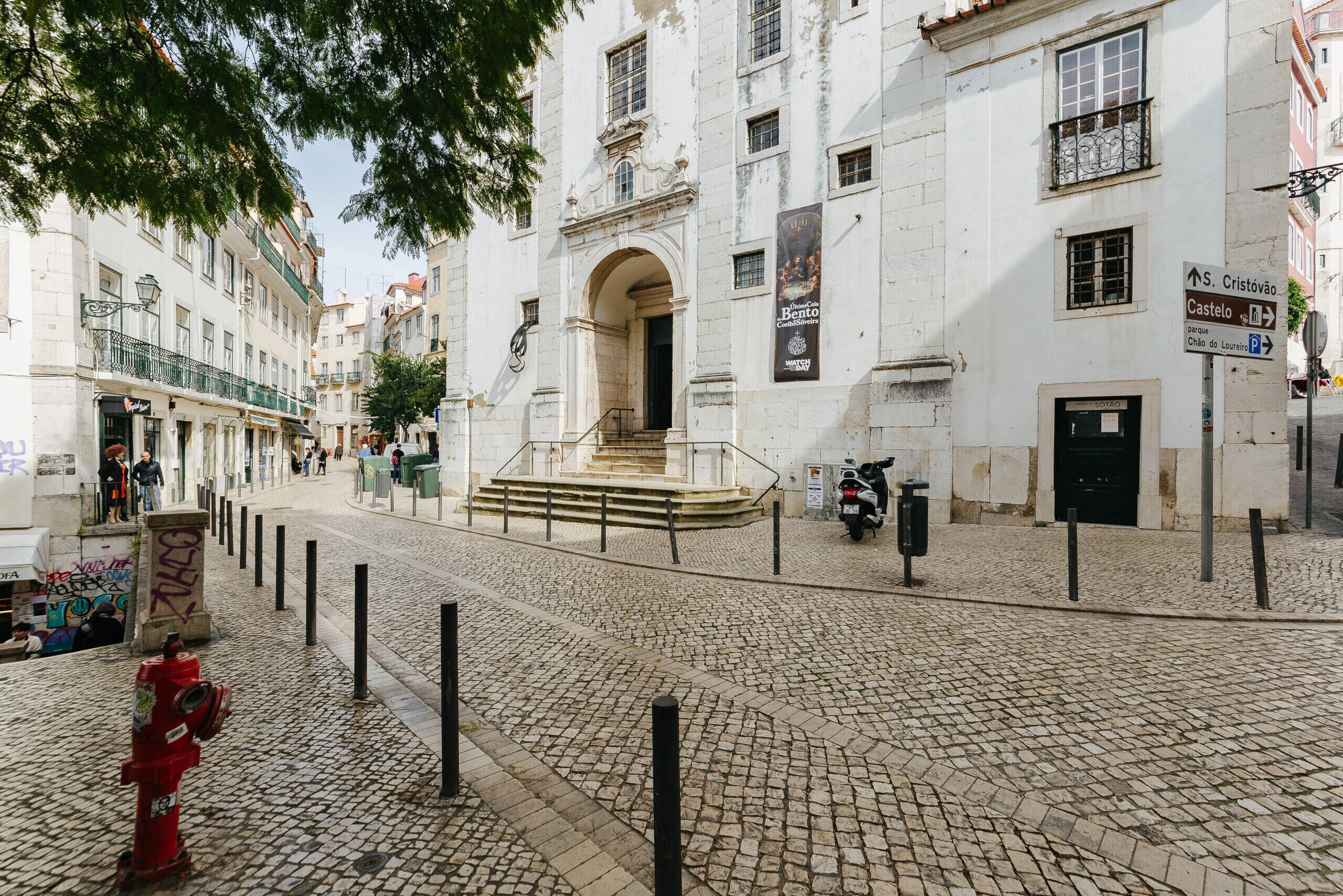 Eine Kopfsteinpflasterstraße mit einem Hydranten, einer Treppe, die zu einem Hauseingang führt, und einem abgestellten Roller.