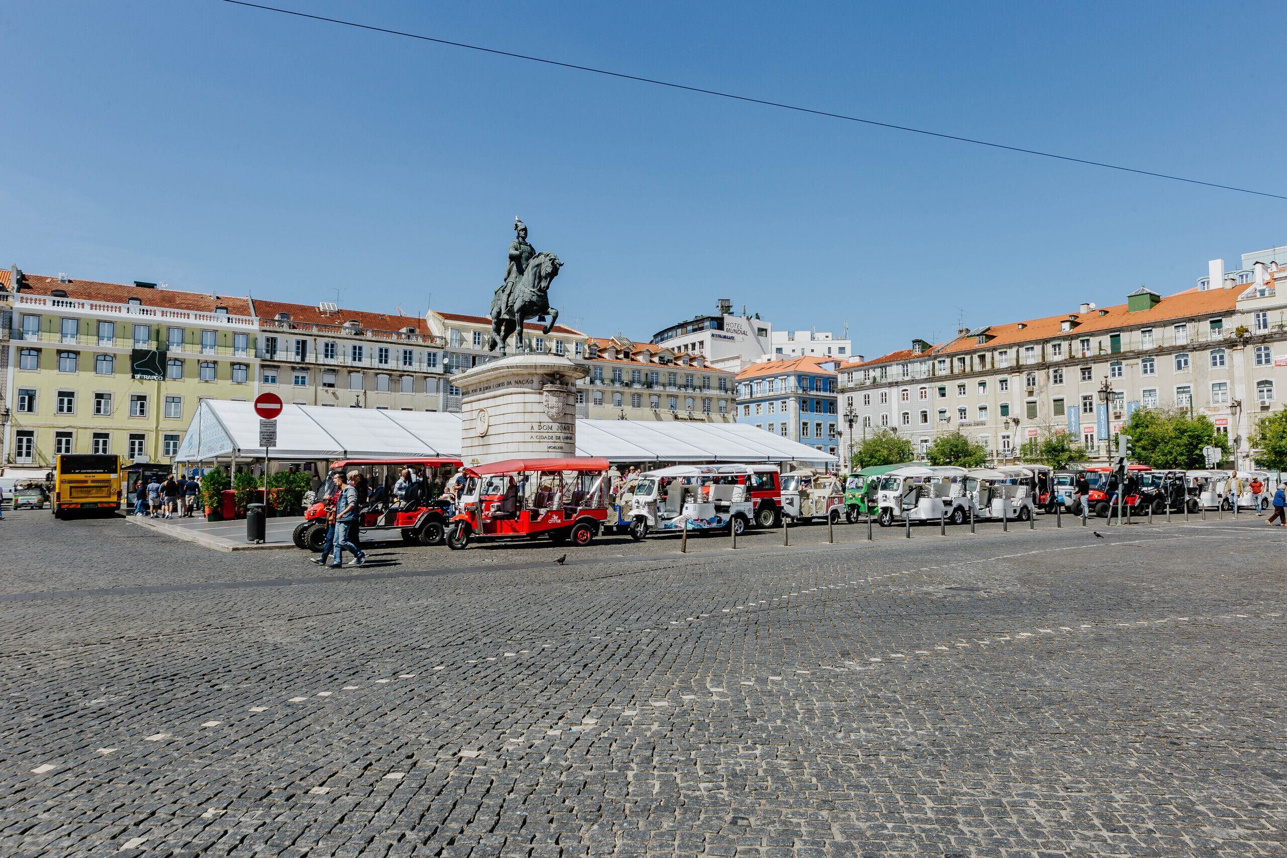 Una plaza adoquinada con una estatua, edificios históricos y camiones de comida.
