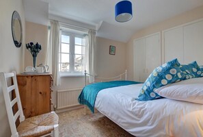 Une chambre à coucher avec un lit, une chaise, une commode, une fenêtre et une lampe bleue.