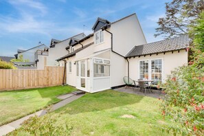 A residential property with a well-maintained lawn, a patio with outdoor furniture, and a wooden fence.