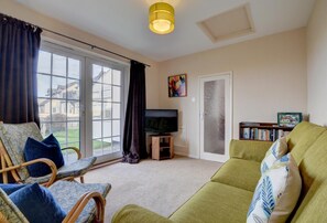 A living room with a sofa, chairs, a television, and a bookshelf.