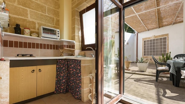 A kitchen with a built-in oven, a microwave, and a sink. There is a window with a view of the patio area.