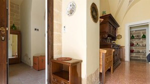 A hallway with a wooden cabinet, a mirror, and a stone wall.