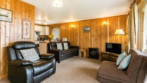 A cozy living room with a leather sofa, a brown couch, and a television. - Four star Lodge with two bedrooms, fabulous views yet close to pubs and beach (Minehead)